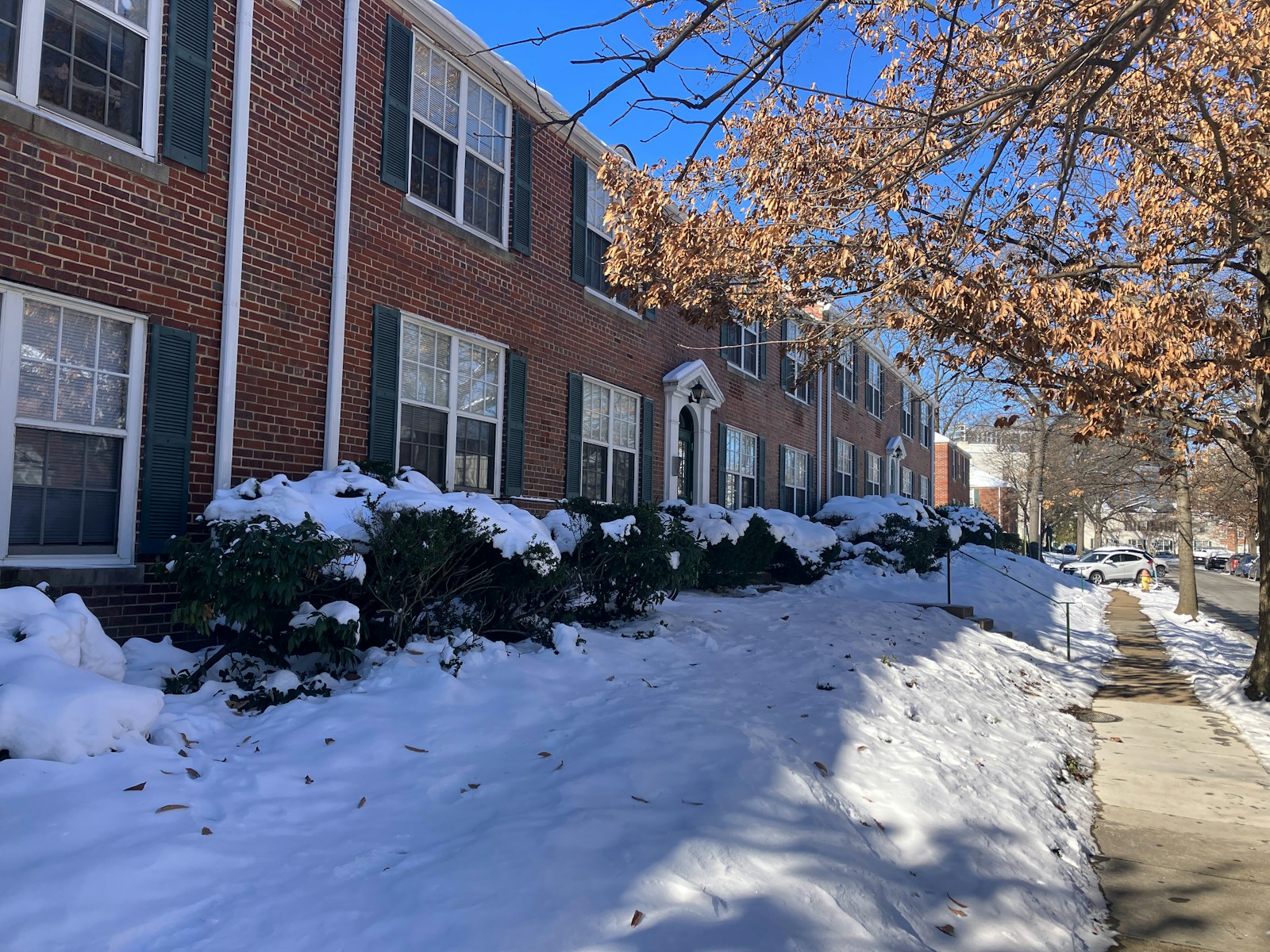 a snow covered sidewalk next to a brick building, condo